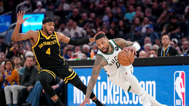 Milwaukee Bucks guard Damian Lillard (0) loses his footing in front of Golden State Warriors guard Moses Moody (4) 